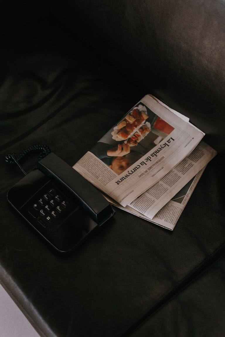 BBC News A vintage black telephone and newspaper on a dark leather sofa, conveying a sense of nostalgia.