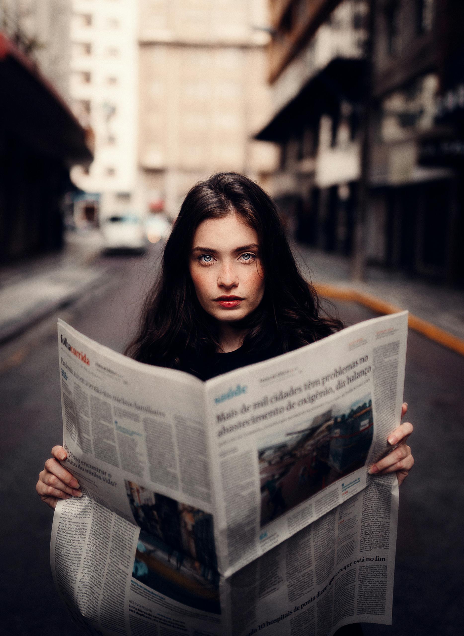 The Occidental News Football Transfer News Portrait of a woman standing in an urban street holding a newspaper.