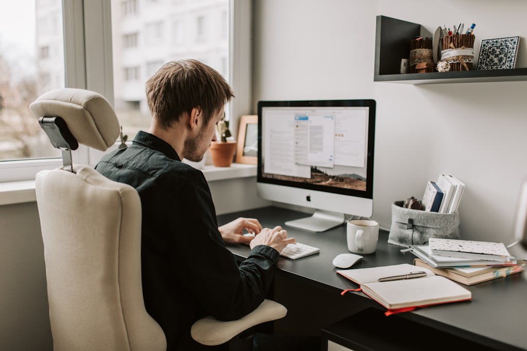 A man in a home office setting working on a computer with a relaxed and focused atmosphere.