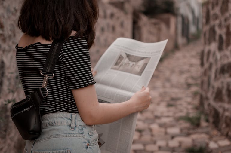 NBCNews: A Comprehensive Exploration of Its Influence, Evolution, and Role in Modern Journalism A woman stands outdoors on a cobblestone path reading a newspaper, embodying leisure and style.