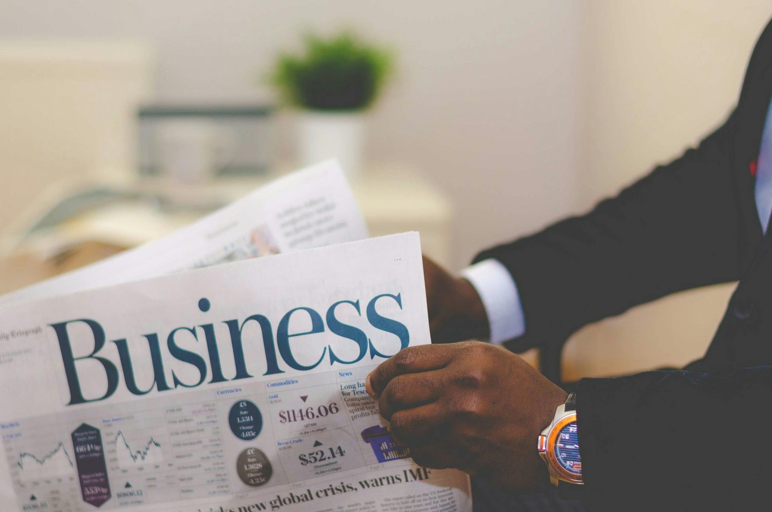 ABC News Close-up of a businessman reading a newspaper indoors, focusing on business headlines.