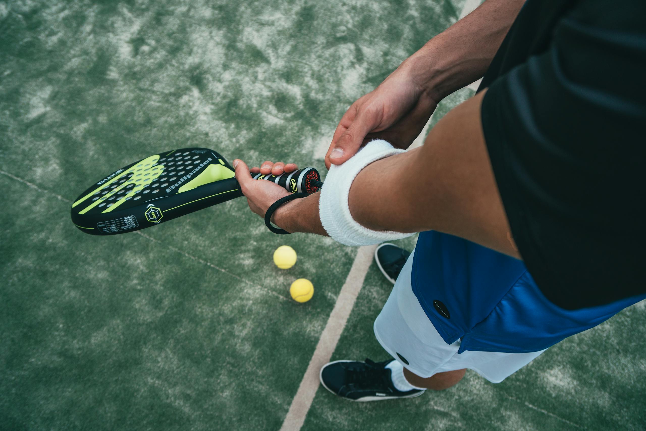 County Sports Close-up of a male padel player adjusting wristband on a court. Sports action focused.