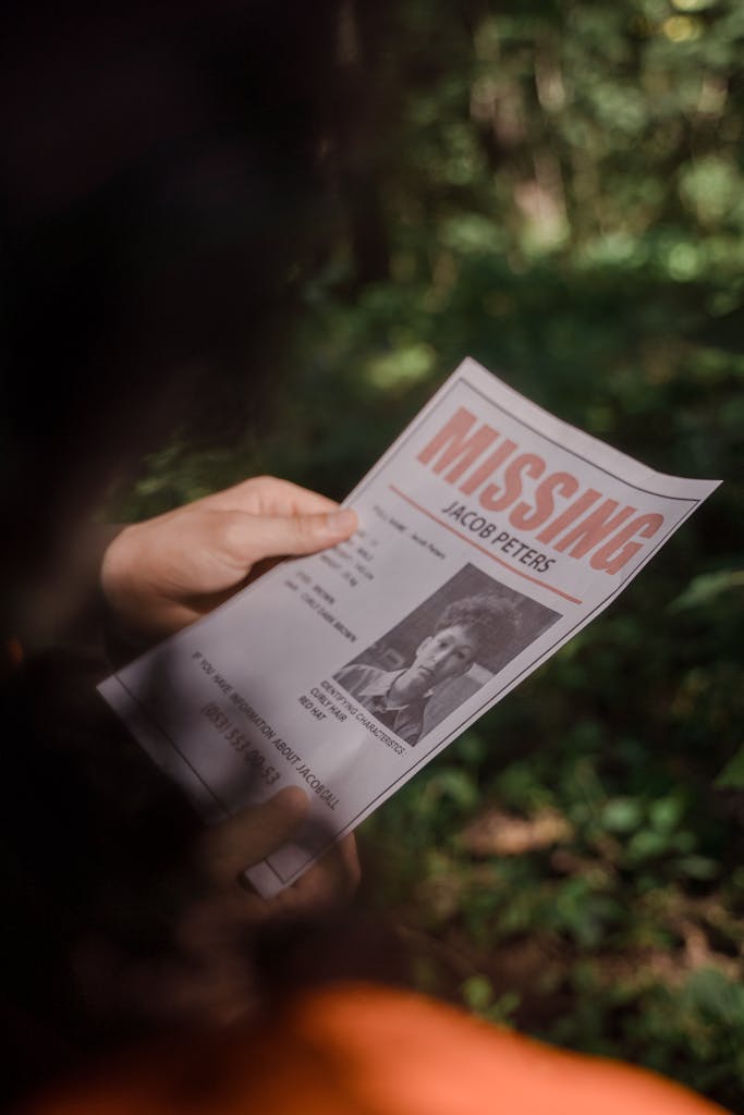ABC News Close-up of a missing person poster being held in a forest environment.