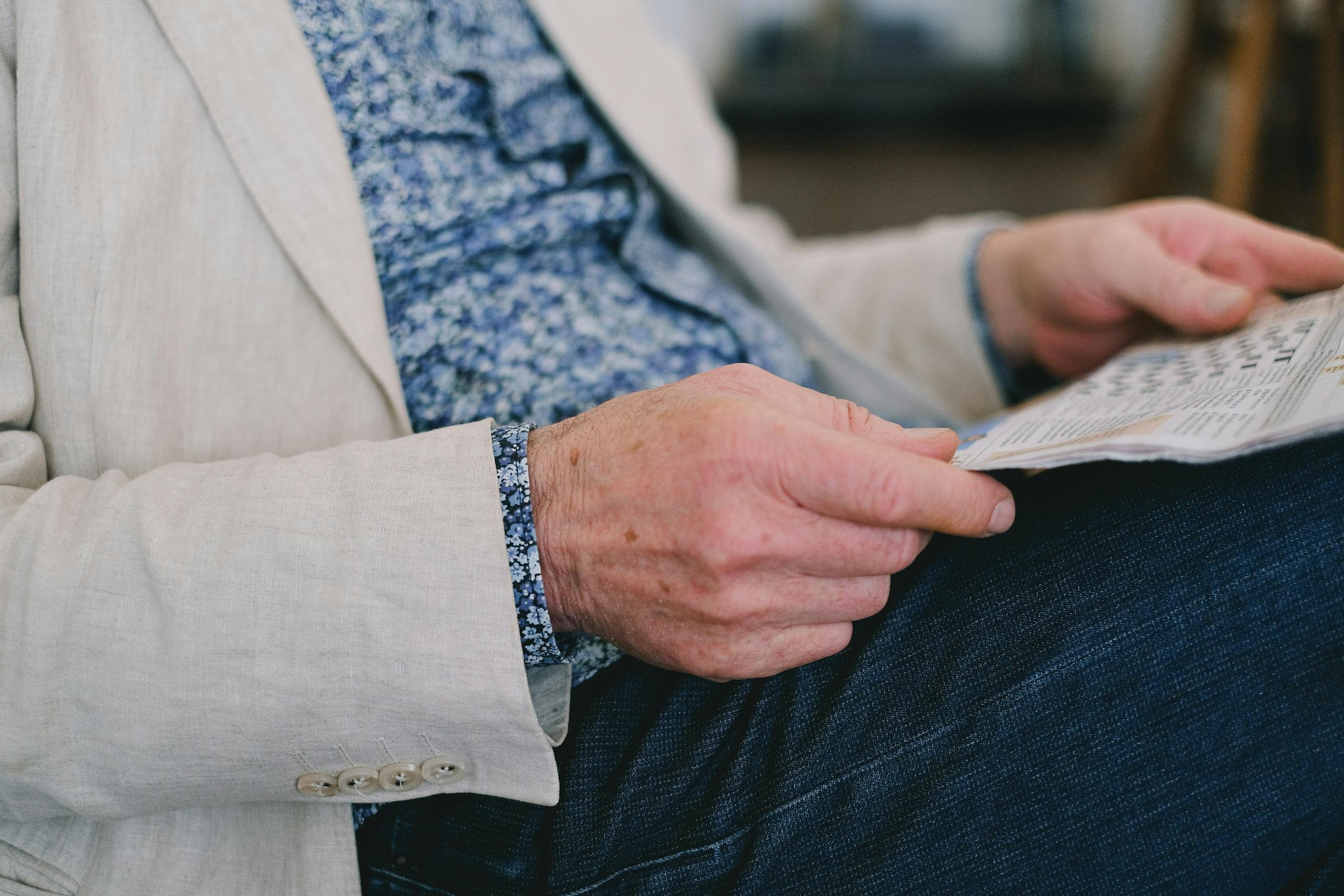The Globe and Mail Crossword Puzzle Close-up of a senior adult's hand holding a newspaper in a calm setting.