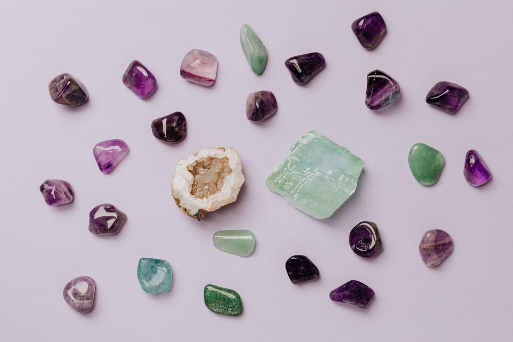 Lola Jade Fielder-Civil Flat lay of assorted polished gemstones including amethyst and jade on a light background.