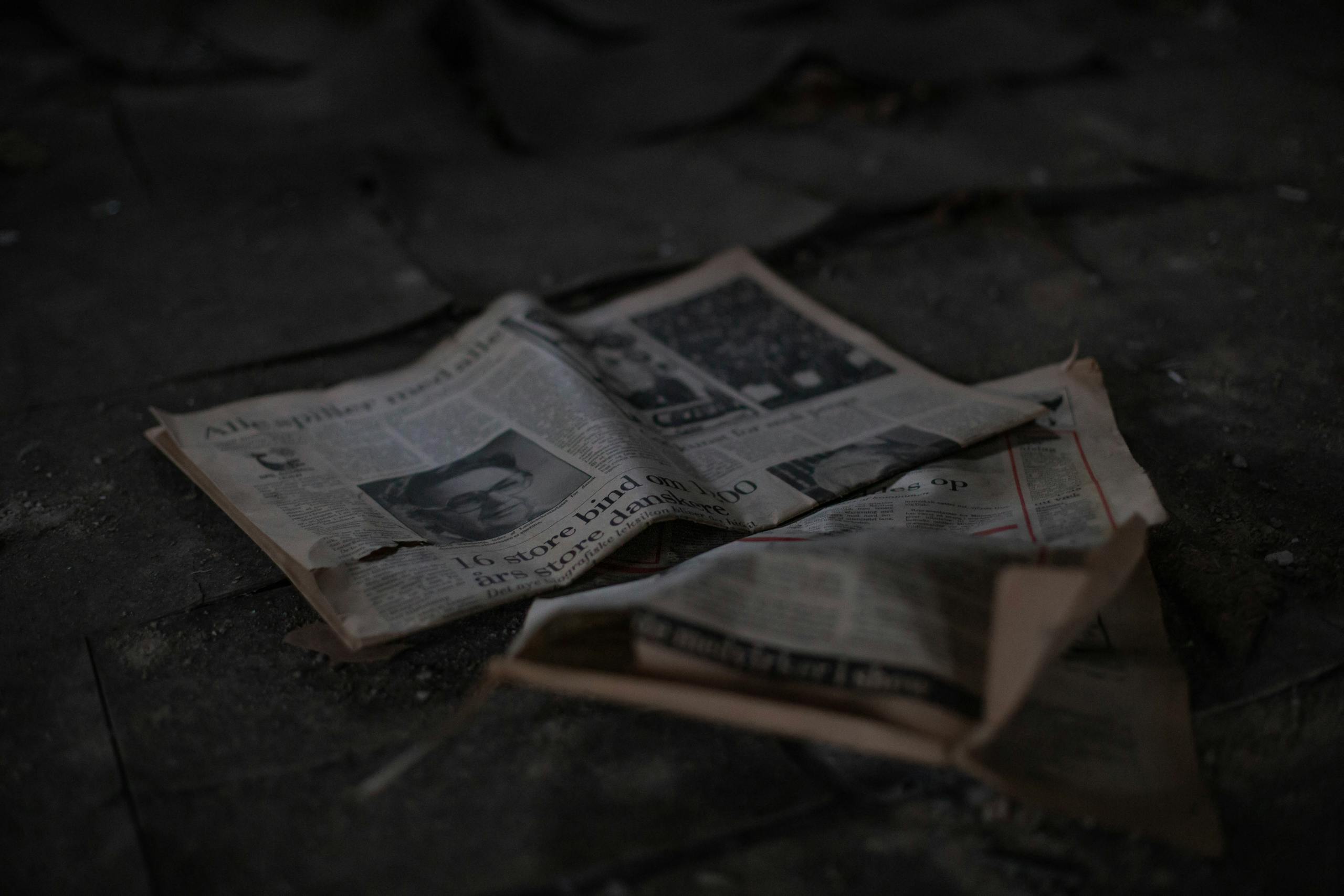 ARY News Scattered newspapers on an outdoor pavement, showcasing decay and abandonment.