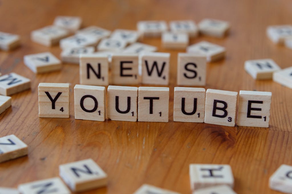 Game News eTrueSports Scrabble tiles spelling words on wooden surface, focusing on YouTube and News.