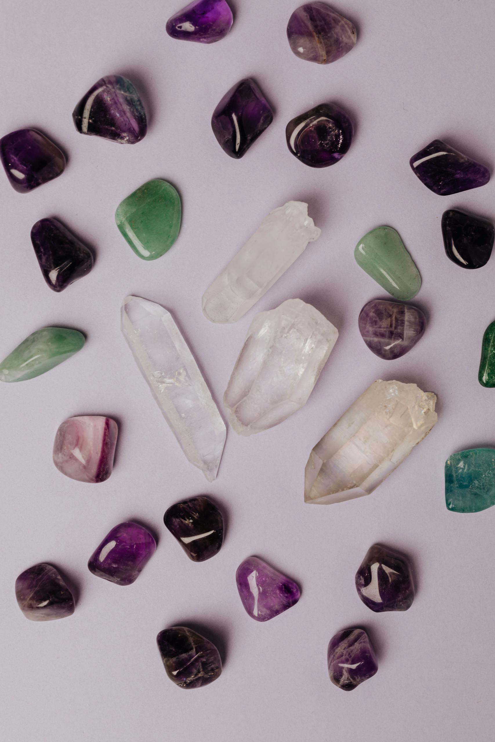 Lola Jade Fielder-Civil Top view of multicolored polished amethyst jade malachite and colorless rock crystal arranged on gray table in studio