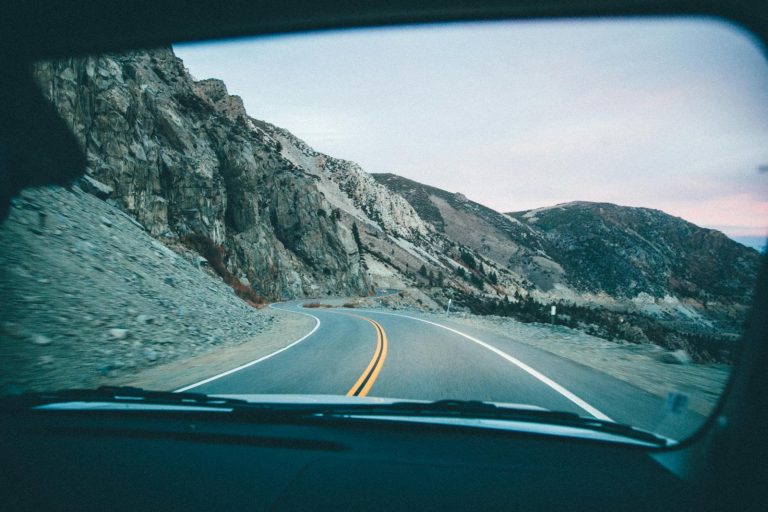 Sotwe View of a winding mountain road through a car windshield during a road trip.