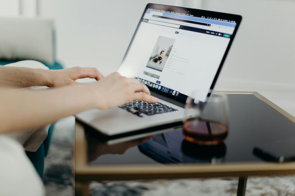 FSI Blogs USA person typing on a laptop in a stylish home office with a glass of drink nearby.