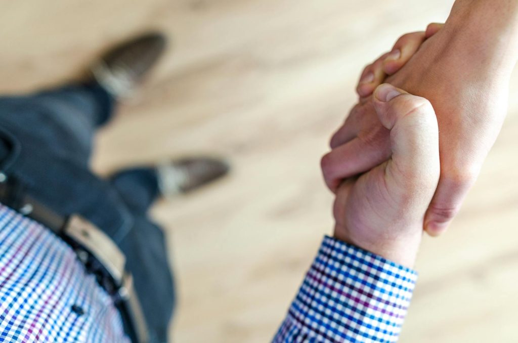 Blazertje Close-up of a handshake between two people inside an office, symbolizing trust and cooperation.