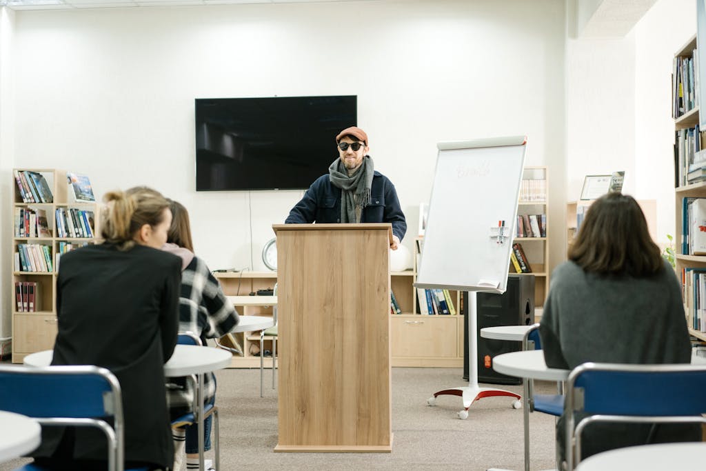 RWU UAR: AA blind instructor using a cane teaches students in a classroom setting.