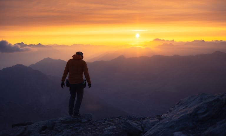 Downnews: A Complete Guide to Understanding Digital News in the Modern Age 2026 vA lone hiker silhouetted against a vibrant mountain sunrise.
