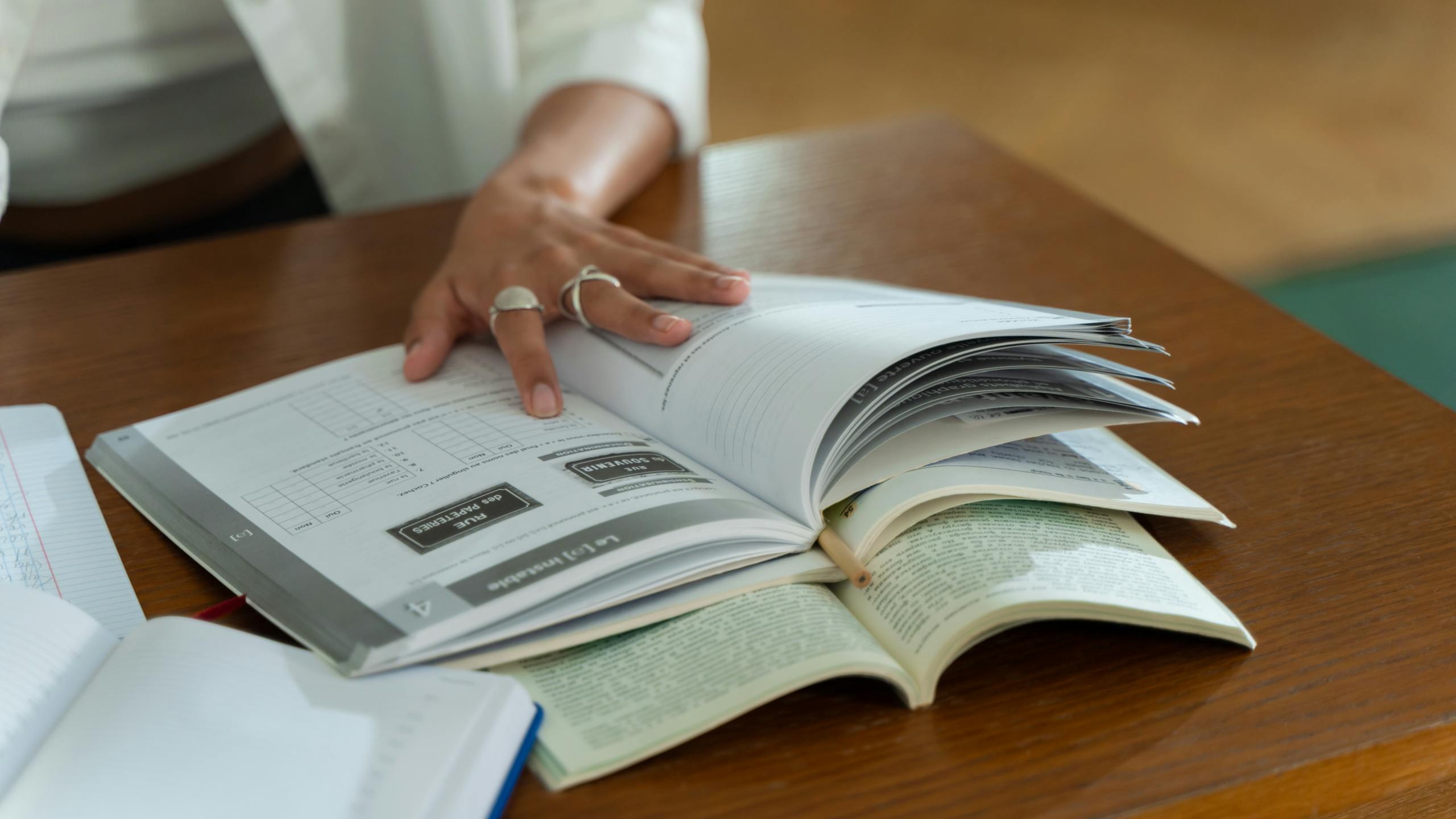 RWU UAR: A Comprehensive Guide to Roger Williams University Academic Records and Services A person studies with open books on a wooden table, focusing on written material.