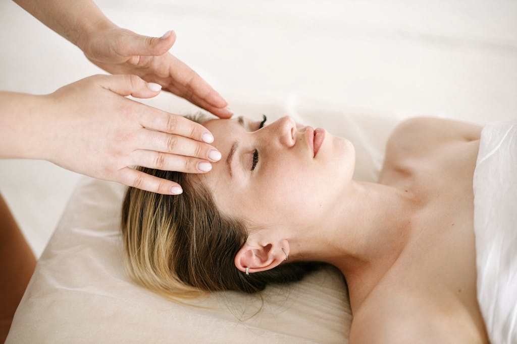  A woman enjoying a relaxing face massage at a spa for therapeutic benefits.