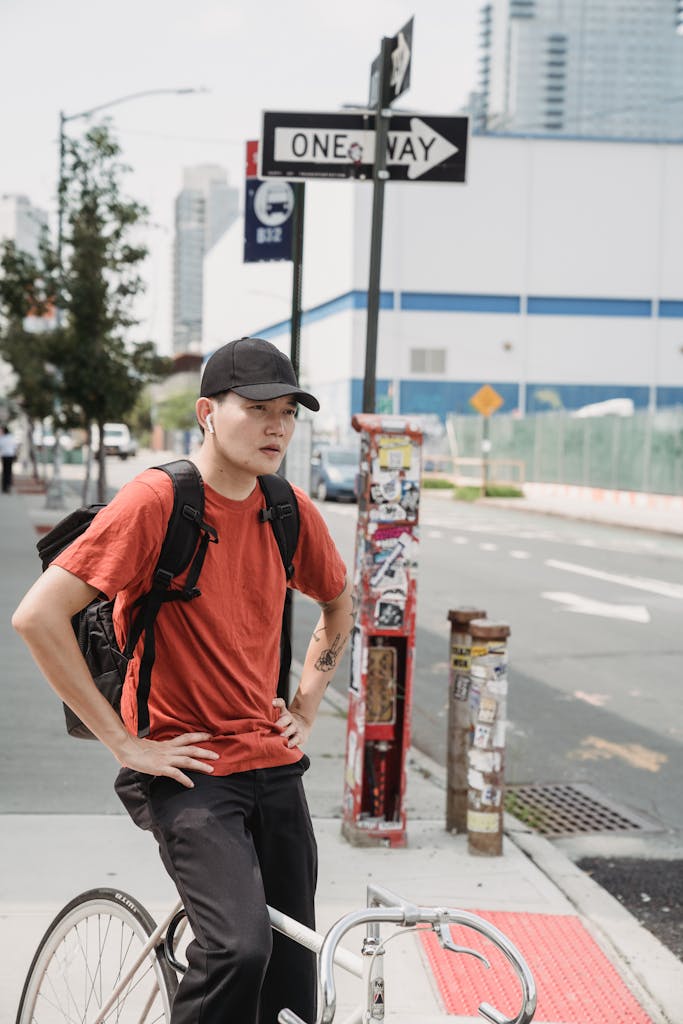 Asian man with a bicycle rests in a city street, showcasing urban lifestyle and freedom.