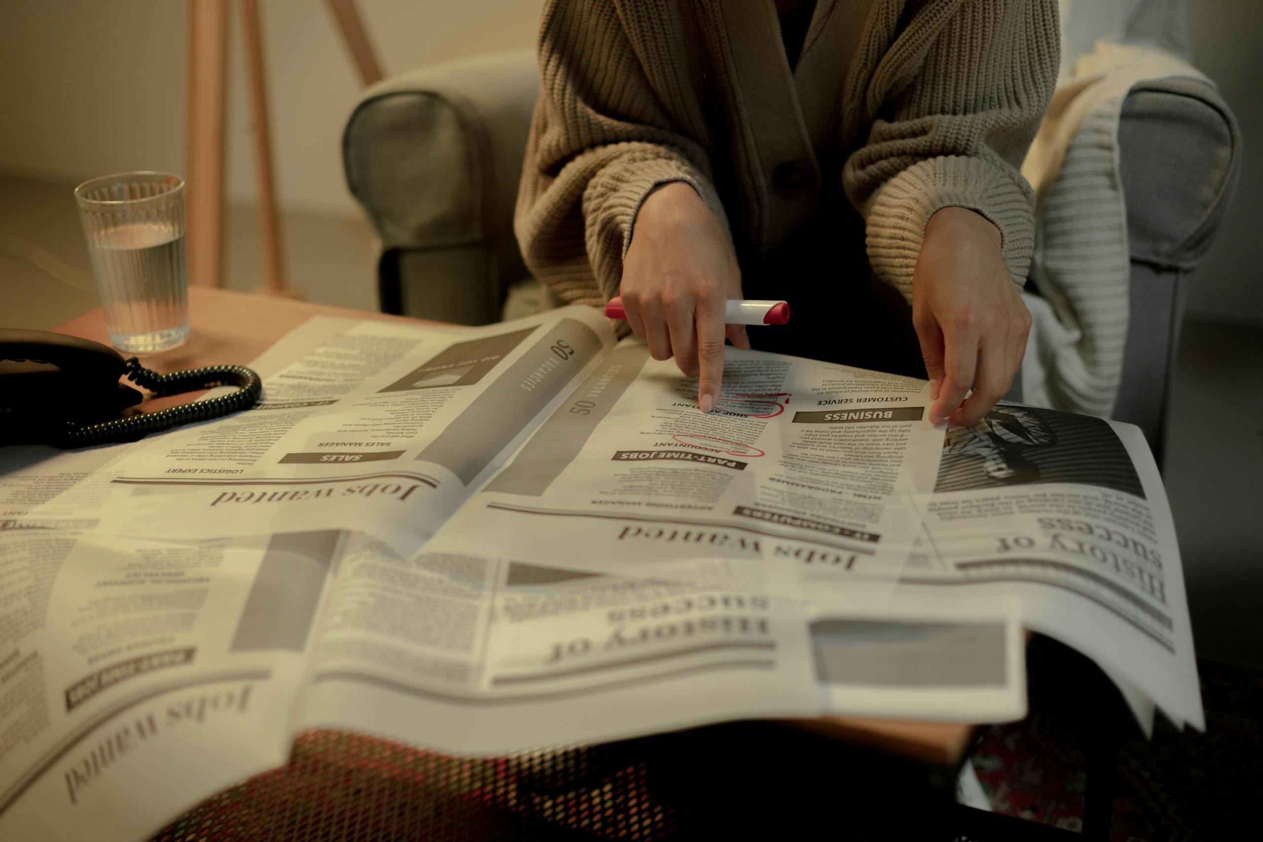 Economic Weekly News Close-up of a woman reading job listings in a newspaper, highlighting employment search.