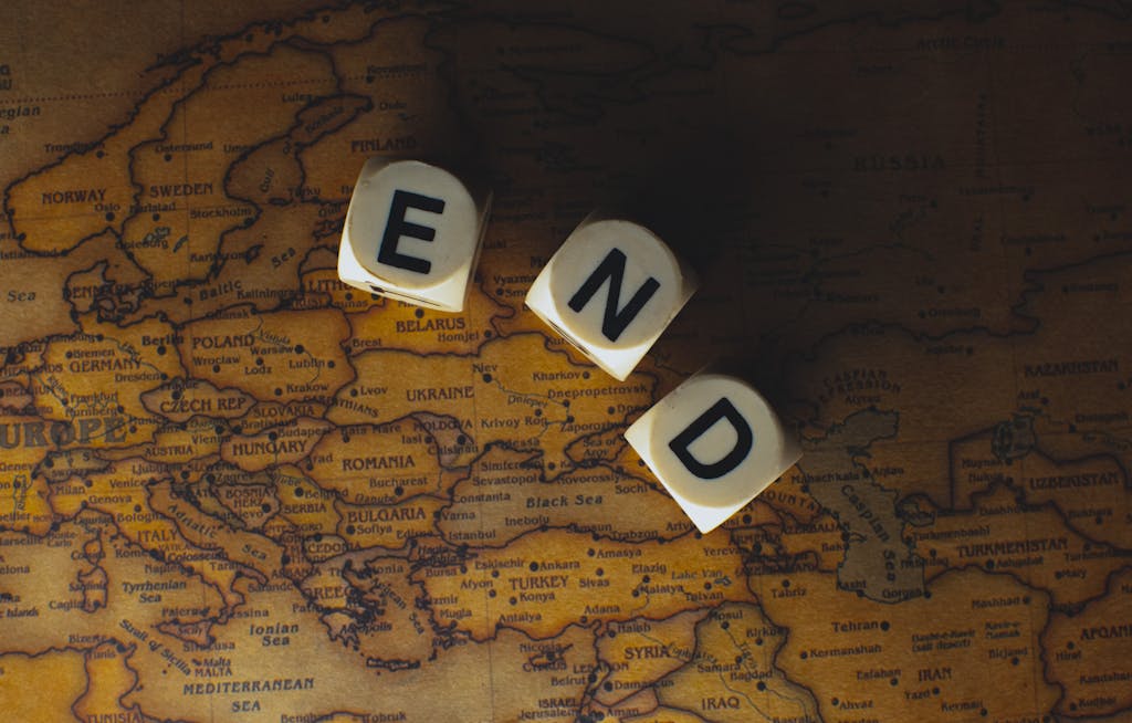Freeoners: Close-up of dice spelling 'END' placed on a map of Europe, symbolizing finish line or travel completion.