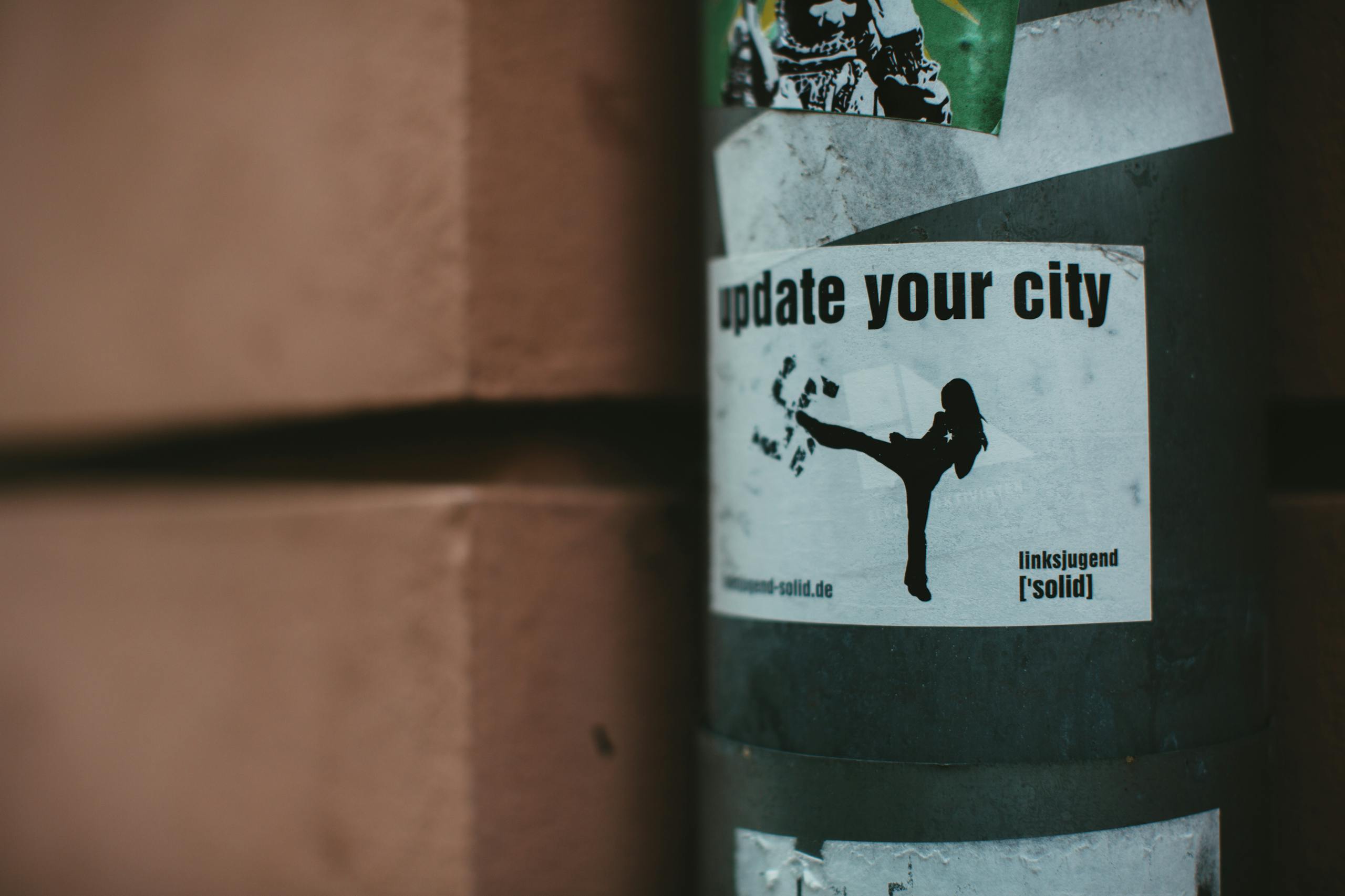 SeaIsleNews Close-up of urban stickers on a city street pole, highlighting street art and activist themes.