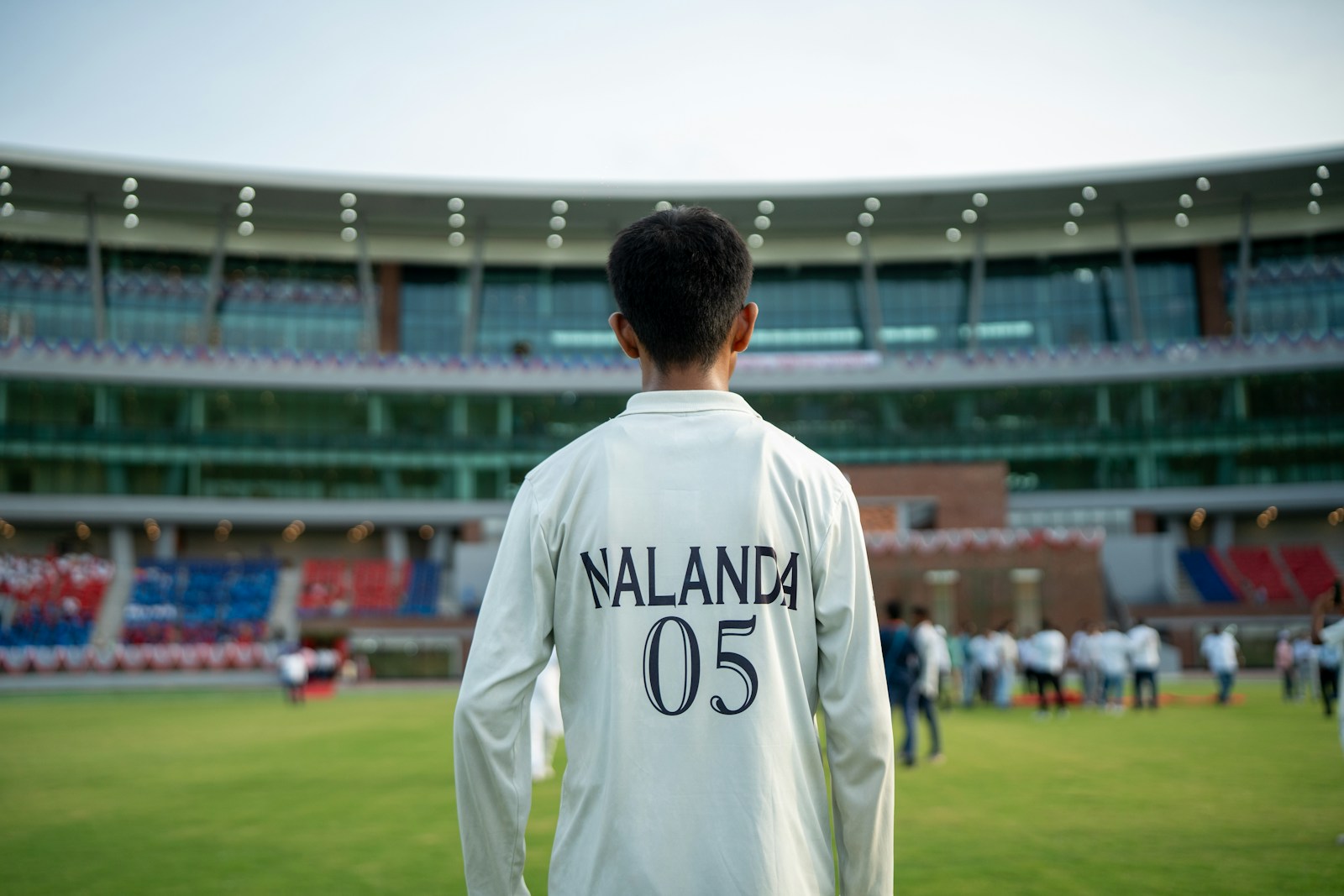 Robert Golob Young cricketer stands on field before stadium crowd.