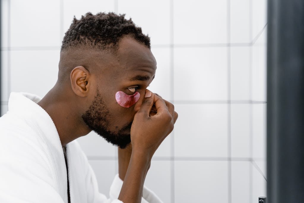 Well Health Tips in Hindi Wellhealthorganic Side view of a man applying under eye mask, focusing on skincare routine.