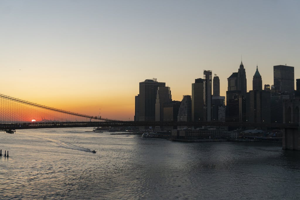 Nova Scola:  
Stunning view of Brooklyn Bridge and Manhattan skyline captured during sunset over the New York City waterfront.