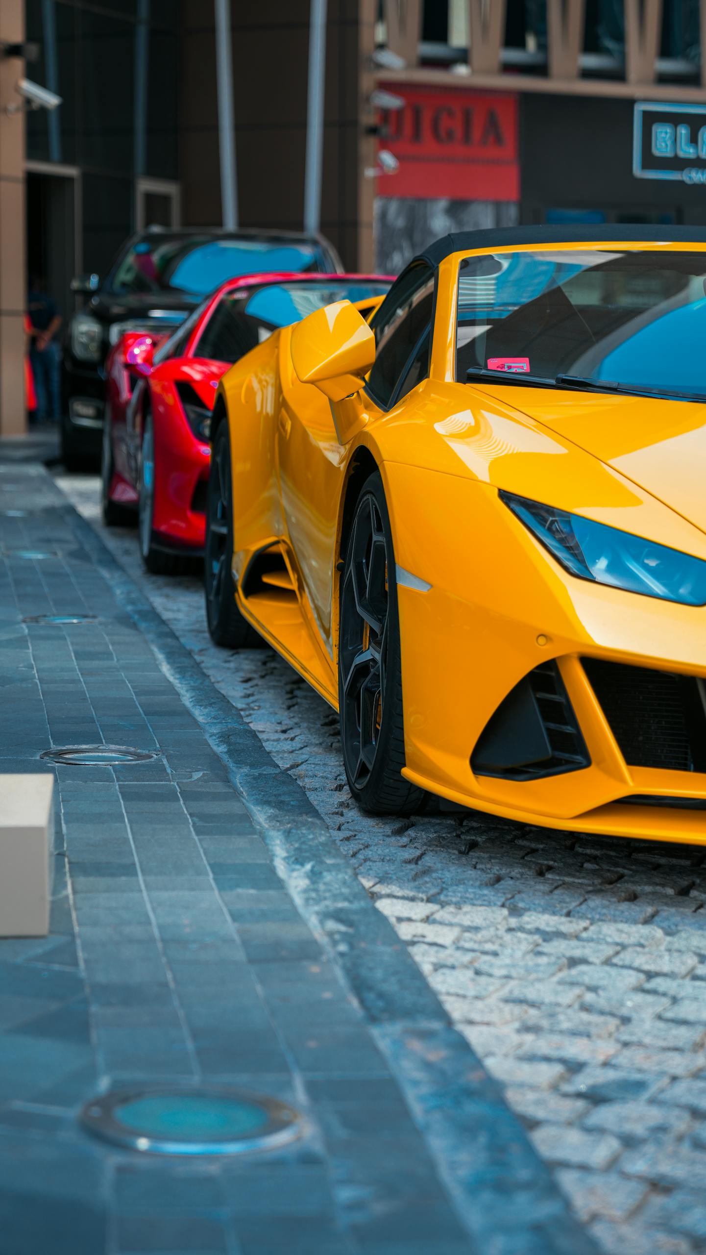 Yellow and red luxury sports cars parked on urban streets in Dubai's vibrant cityscape. Rent Convertible Dubai