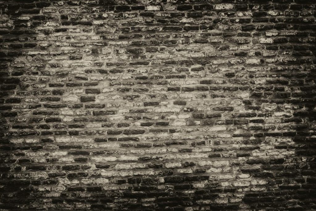 Sixmagazine  Grayscale textured brick wall background with rough surface.