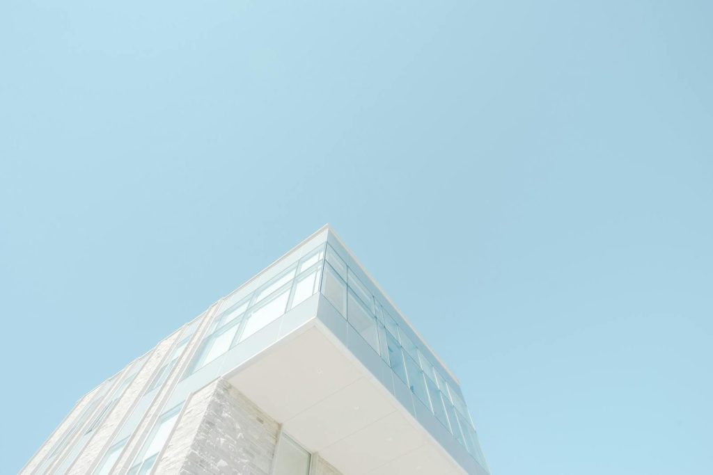 Newstook A low-angle shot of a modern building with a glass facade against a bright blue sky in London, Canada.