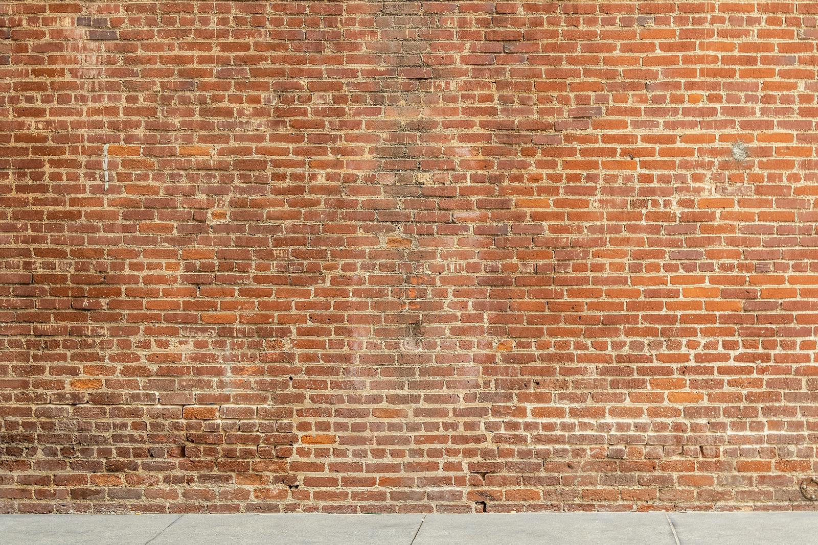 MMSBRE Detailed image of a textured red brick wall with a concrete base, ideal for architectural and design backgrounds.