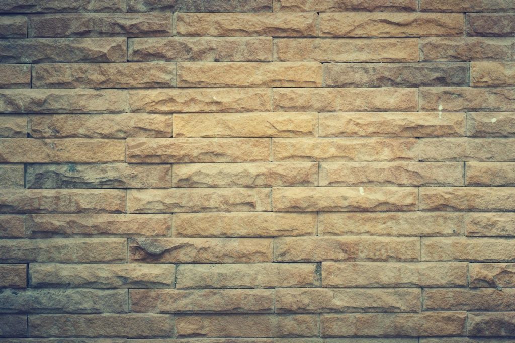 Permanentad Newstook Rustic brown brick wall with textured pattern, perfect for backgrounds and design elements.