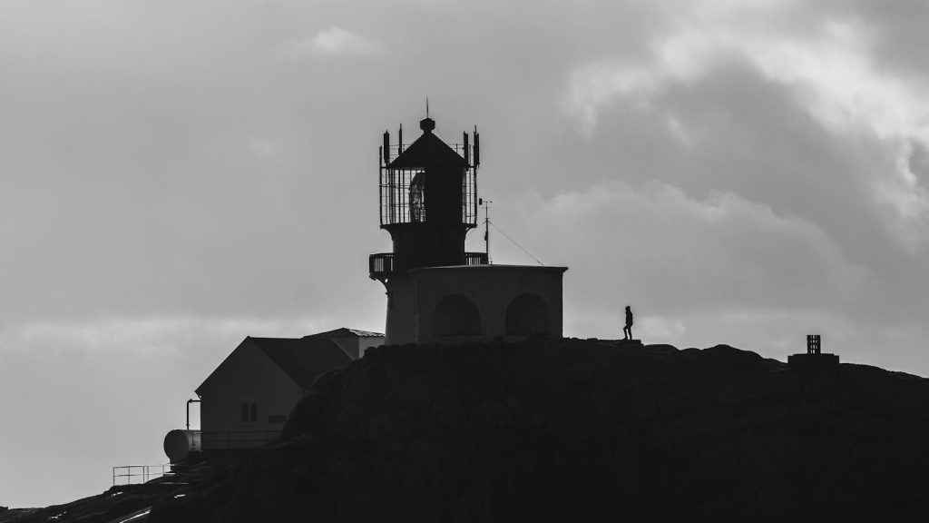 Silhouette of Lindesnes Lighthouse with dramatic sky, highlighting Norway's coastal allure.