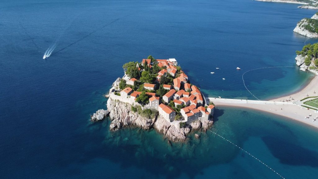 ibomma1.com A breathtaking aerial view of the picturesque Sveti Stefan Island, Montenegro, surrounded by azure waters.
