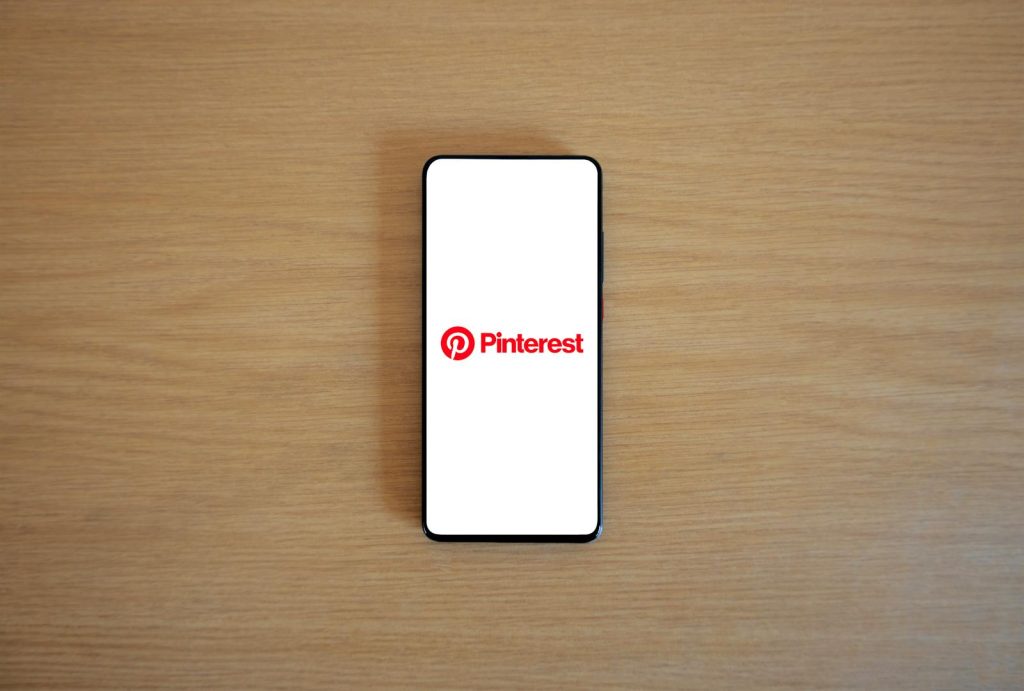 Ventsmagazine.cloud Smartphone with Pinterest logo on screen placed on a wooden surface, minimalistic tech concept.