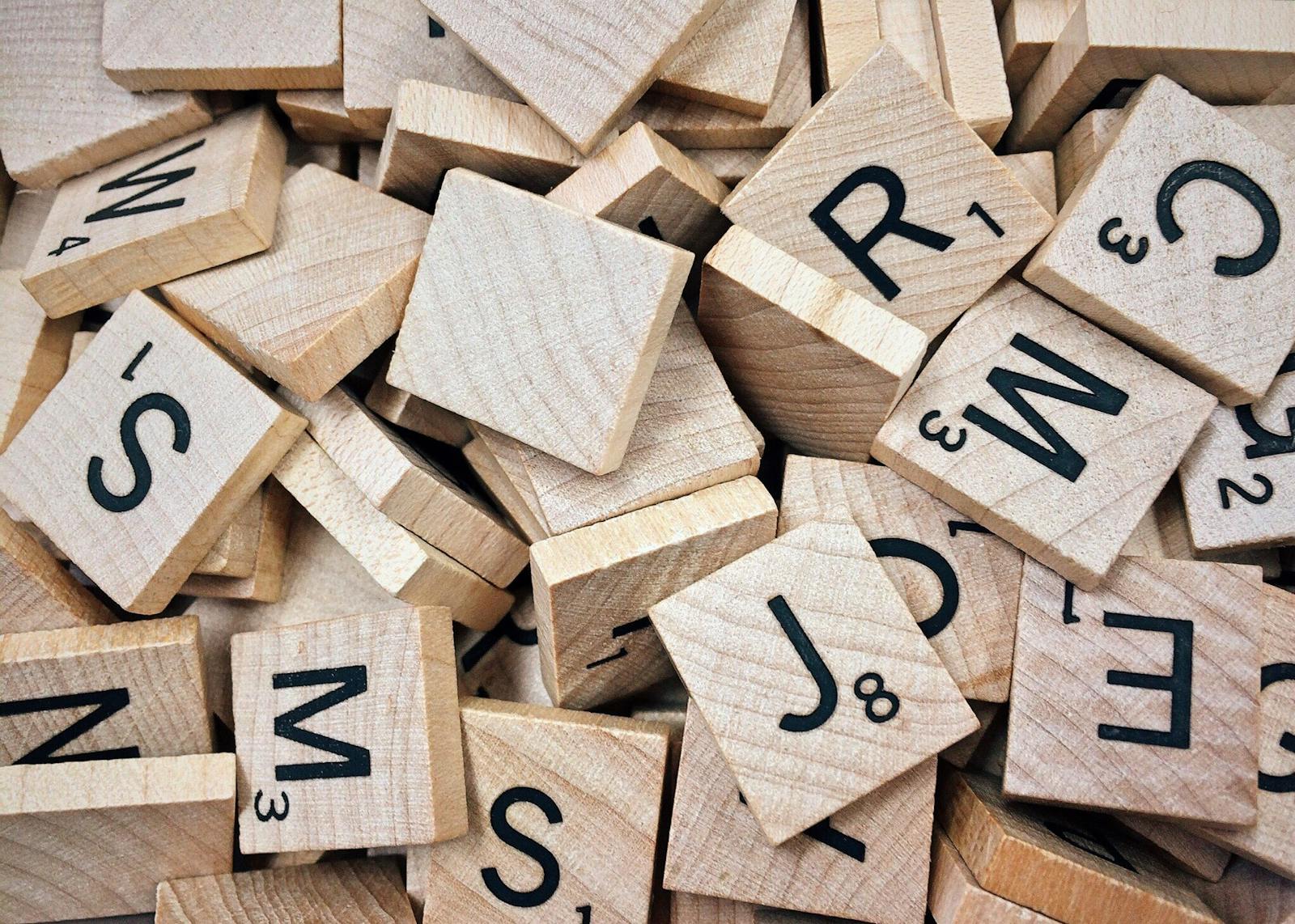 Shop Sunnylife Giant Jumbling Tower A collection of wooden Scrabble tiles with letters and numbers stacked randomly.
