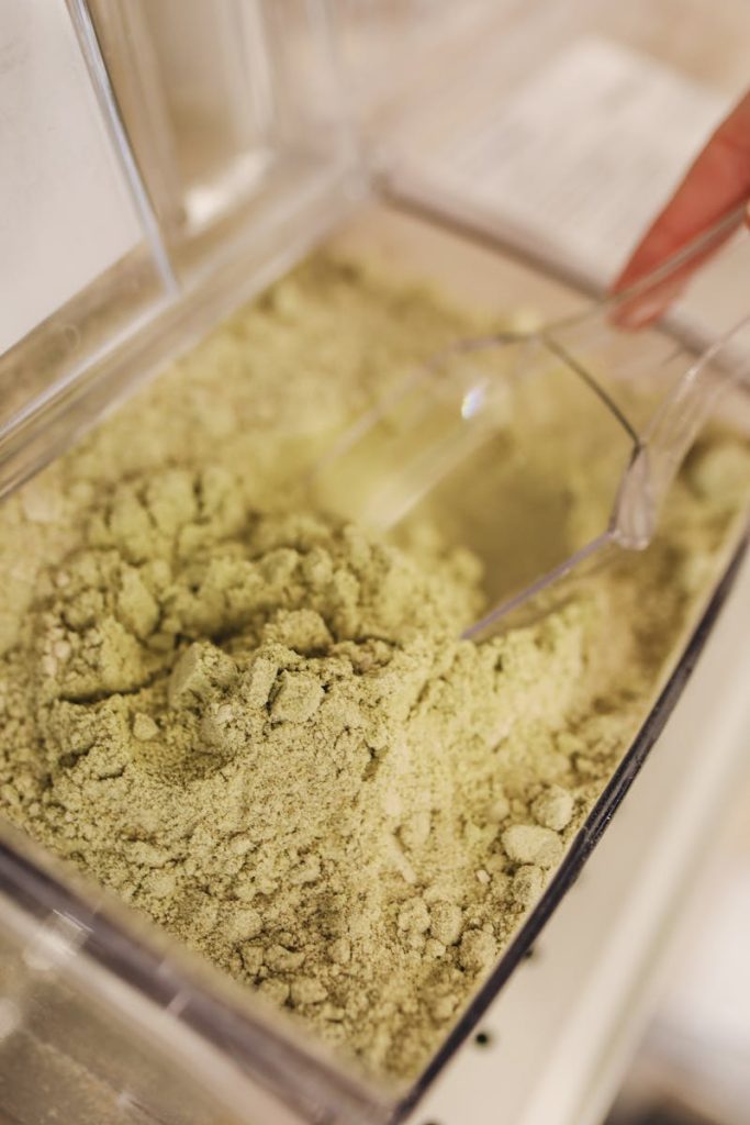 Vivid close-up shot of culinary grade matcha powder with scooper in a container.