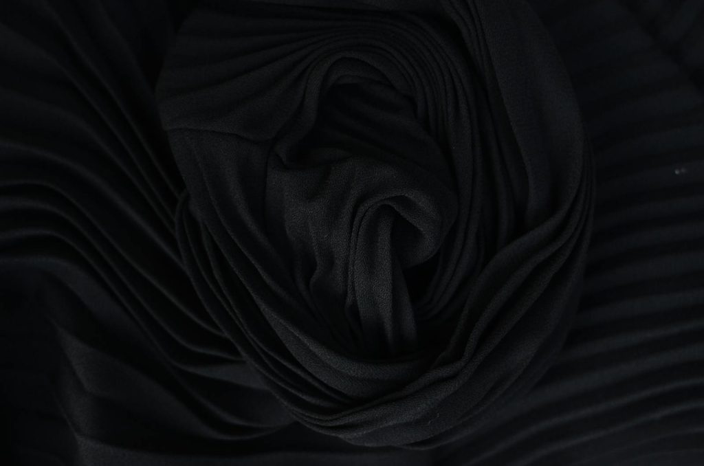 Top view of abstract background representing wavy creased black silk fabric in twilight