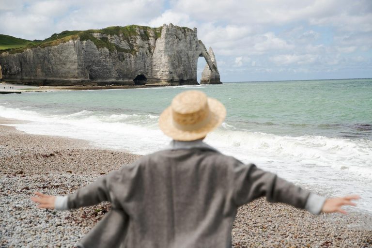 Uitly com Faceless woman admiring the iconic cliffs at Étretat, Normandy, France.