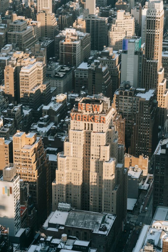 Aerial view of multistory hotel facade with signboard on rooftop located on street of New York City