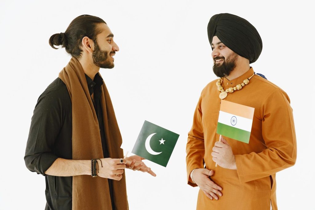 Pak vs Ind Two men, holding Indian and Pakistani flags, engage in friendly conversation.