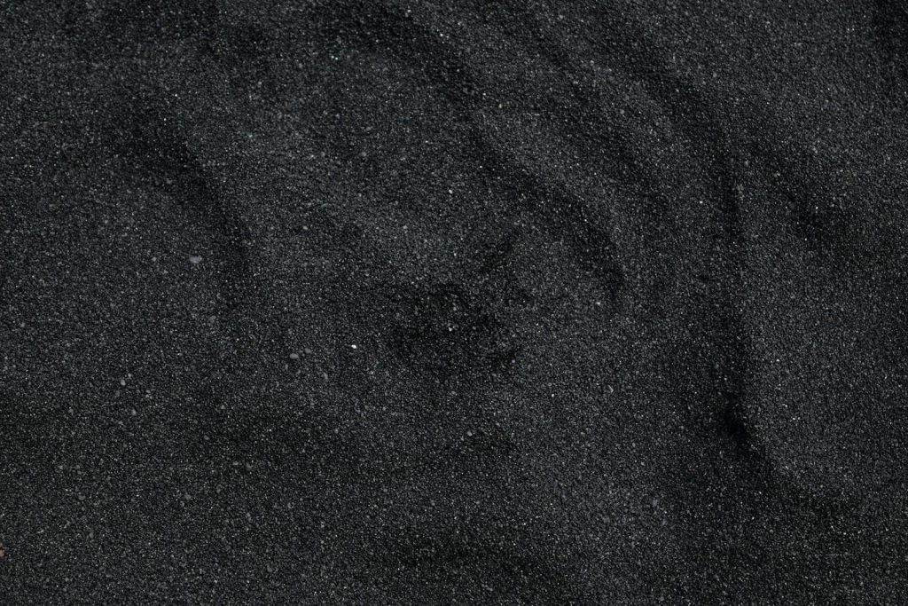 mansutfer Close-up of black sand texture from Waimea Beach in Hawaii. Ideal for backgrounds.