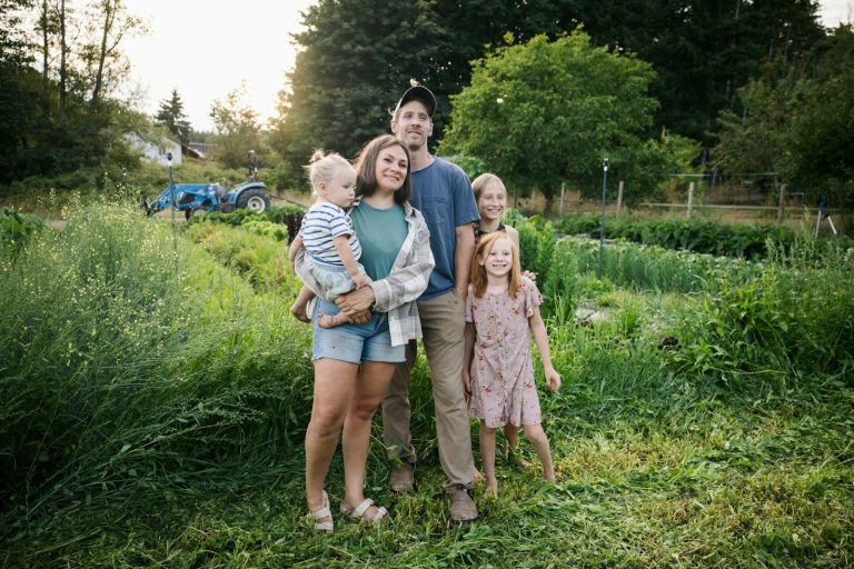 lufanest Family standing in a lush green field with tractor.
