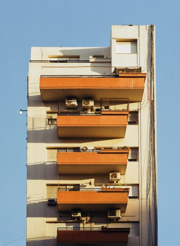Modern apartment building with orange balconies and air conditioners.