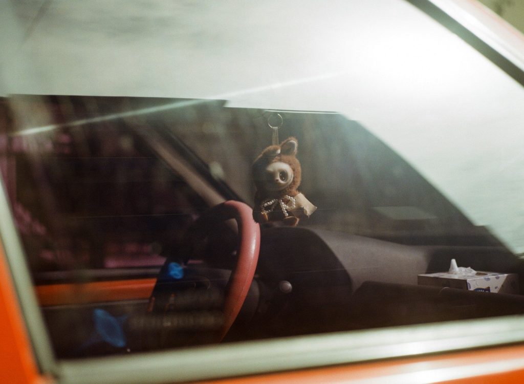 A fuzzy teddy bear hangs from a car's rearview mirror.