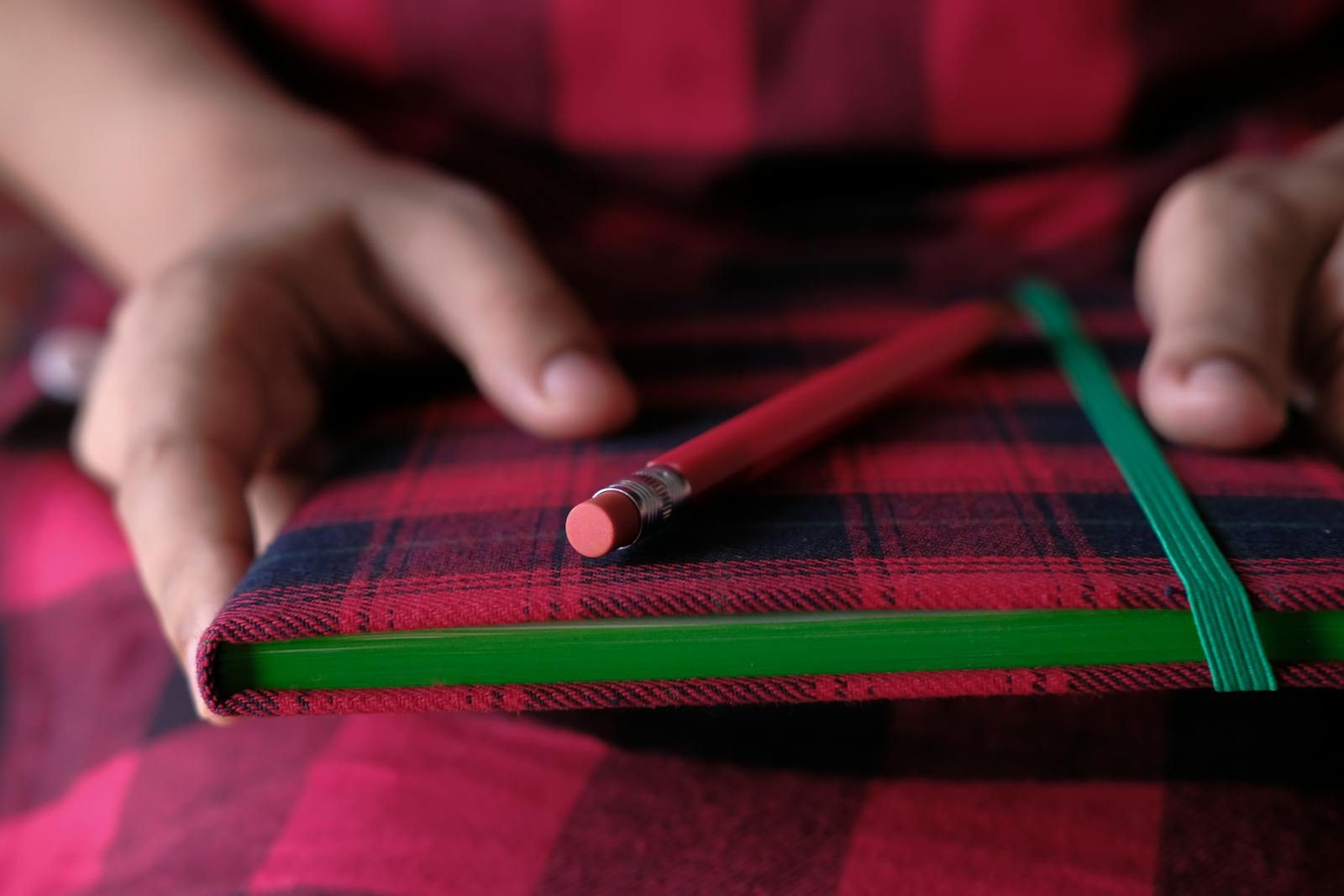 Memorandum to Cabinet: A Complete Guide to Purpose, Structure, and ProcessRed plaid notebook and pencil held by hands, close-up view.